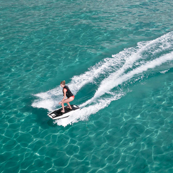 A girl is seen effortlessly gliding over a crystal-clear turquoise sea on an Awake RÄVIK 3 electric jetboard. 