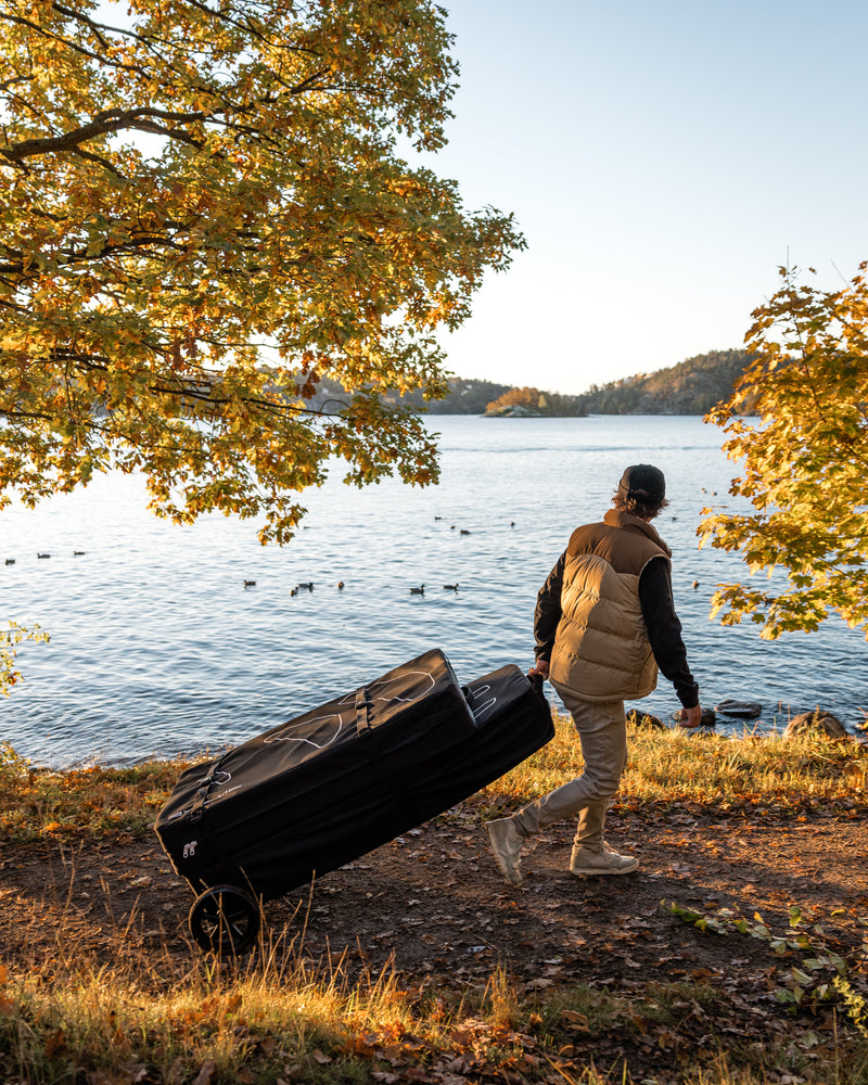 Man carrying Awake VINGA Board Bag Kit from the lake