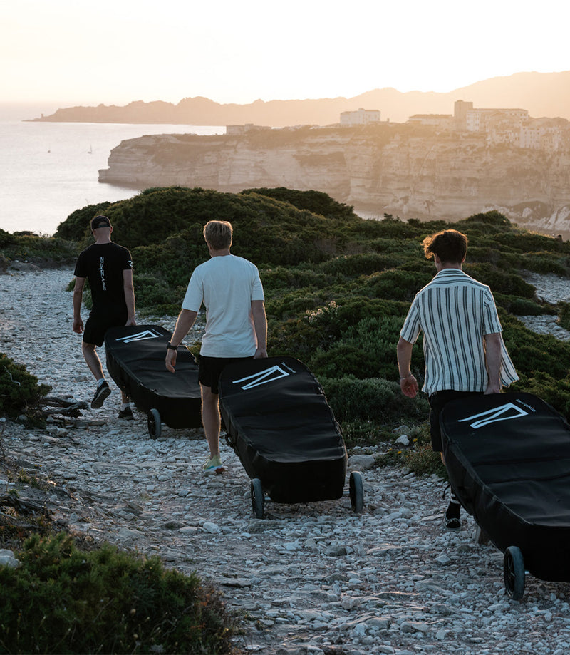 Three men carrying the RAVIK Board Bag Kits to the Beach