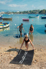 A woman laying out the Awake Beach Mat by a port