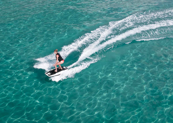 A girl is seen effortlessly gliding over a crystal-clear turquoise sea on an Awake RÄVIK 3 electric jetboard.