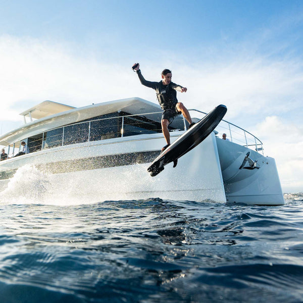 A man jumping over the water on a RAVIK S with the backdrop of a yacht.