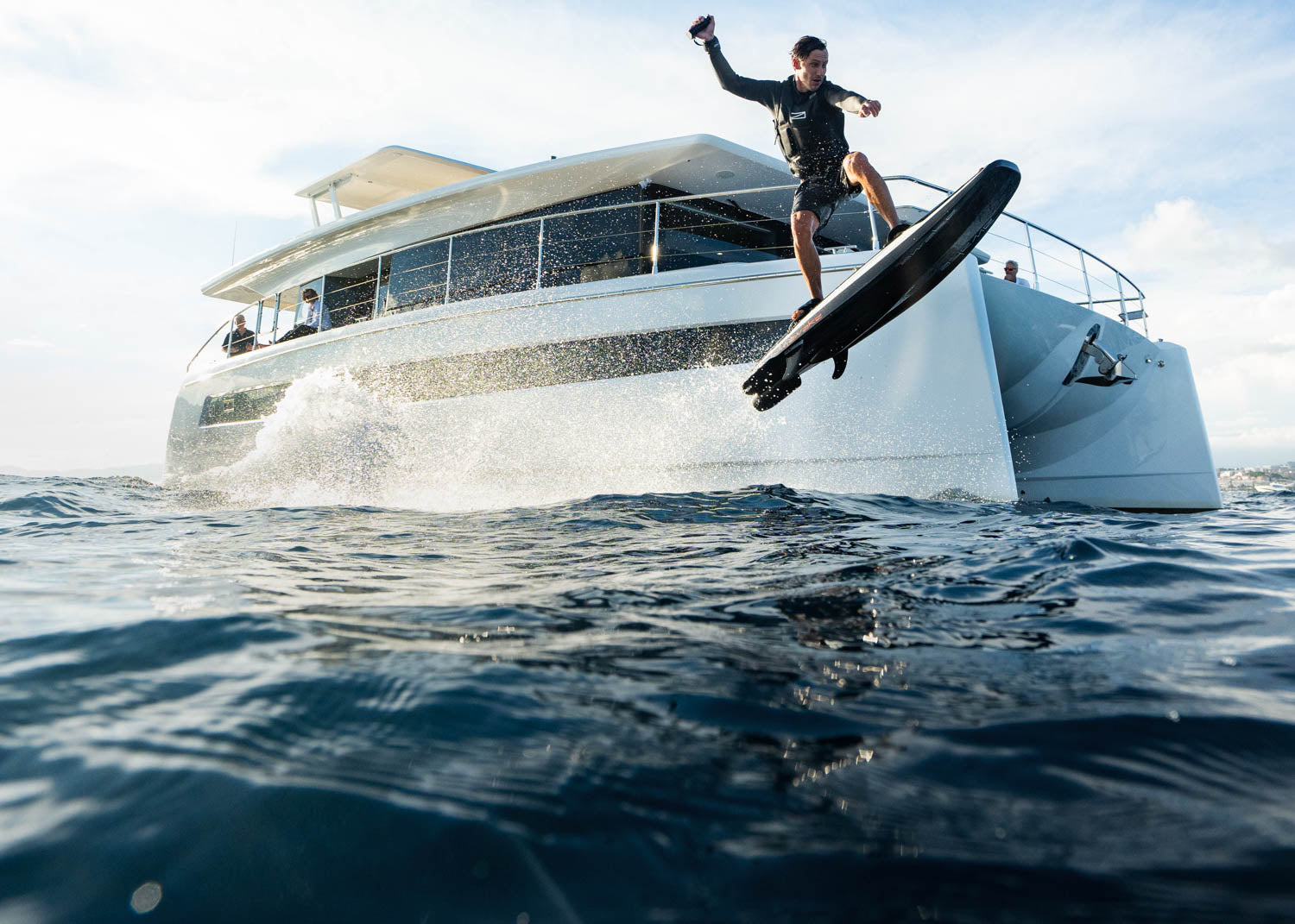 A man jumping over the water on a RAVIK S with the backdrop of a yacht.